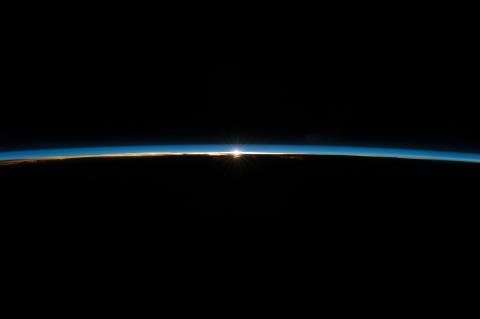 De zon, glurend door de dunne atmosfeerlijn van de Aarde